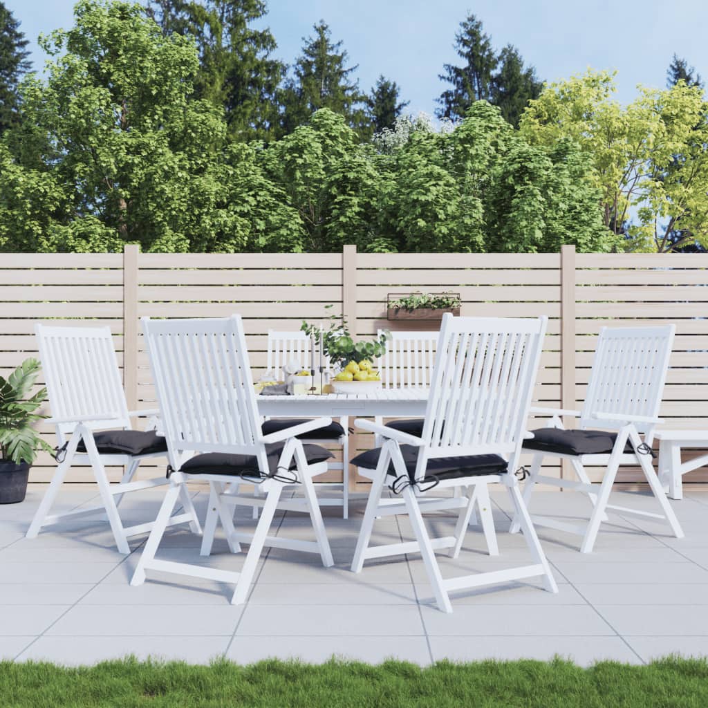 Coussins anthracite sur des chaises blanches autour d’une table de jardin, mobilier non inclus.