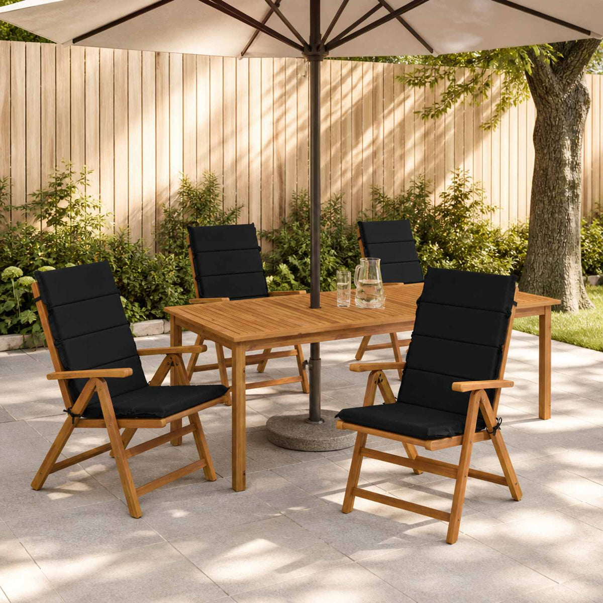 Coussins noirs à dossier haut sur des chaises autour d’une table de jardin, mobilier non inclus.