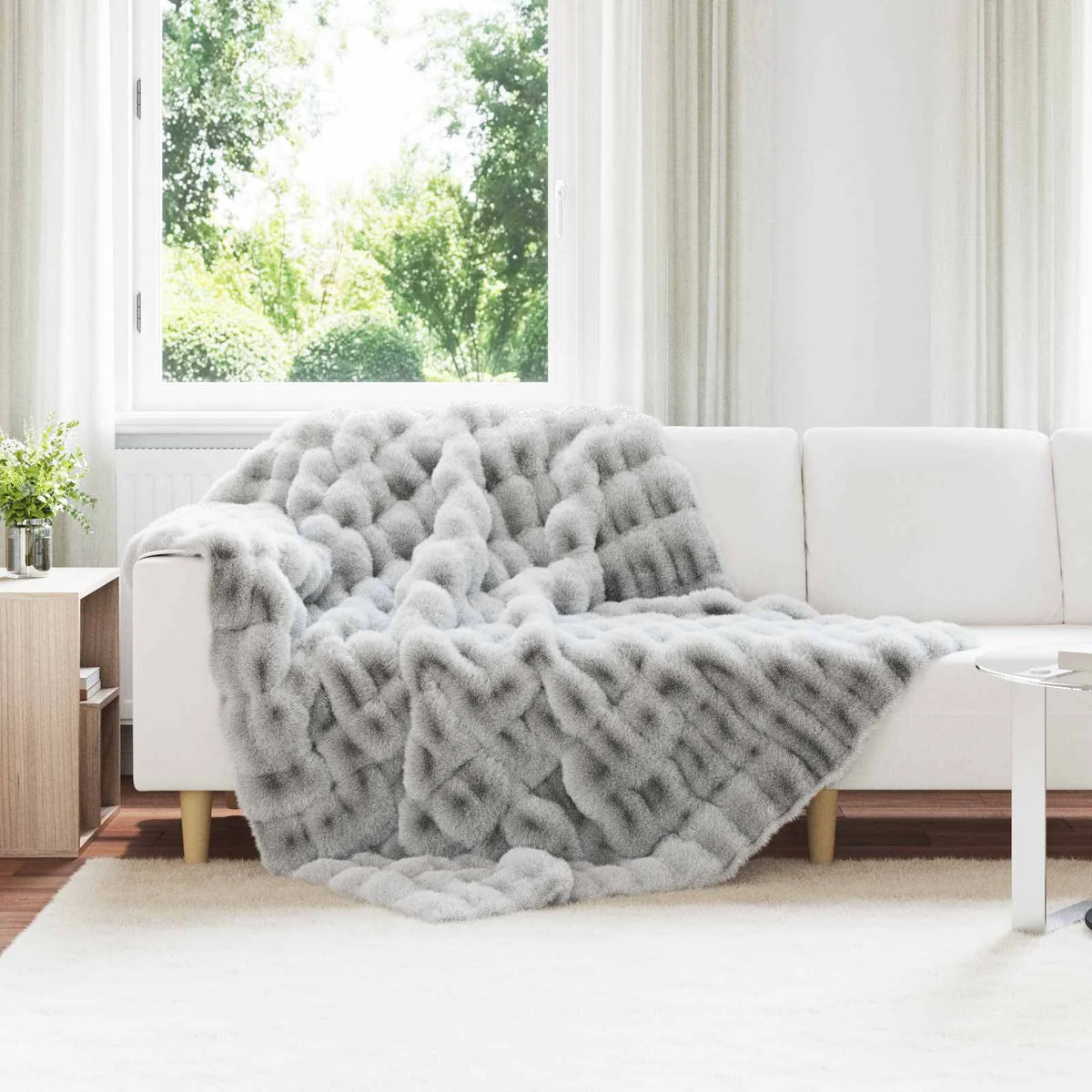 Couverture Antidérapante, coloris gris, drapée sur un canapé blanc