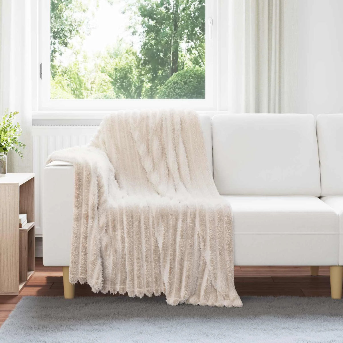 Couverture Beige, coloris beige, drapée sur un canapé blanc