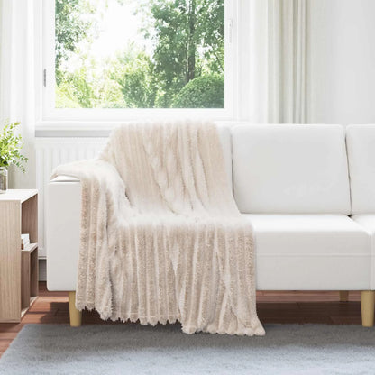 Couverture Beige, coloris beige, drapée sur un canapé blanc