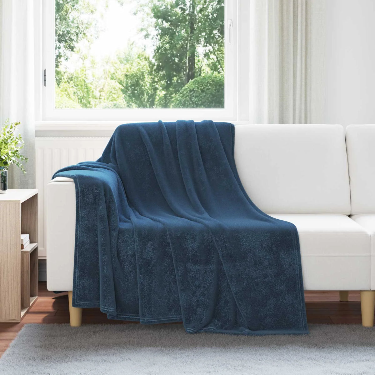 Couverture Bleu Marine, coloris bleu marine, drapée sur un canapé blanc