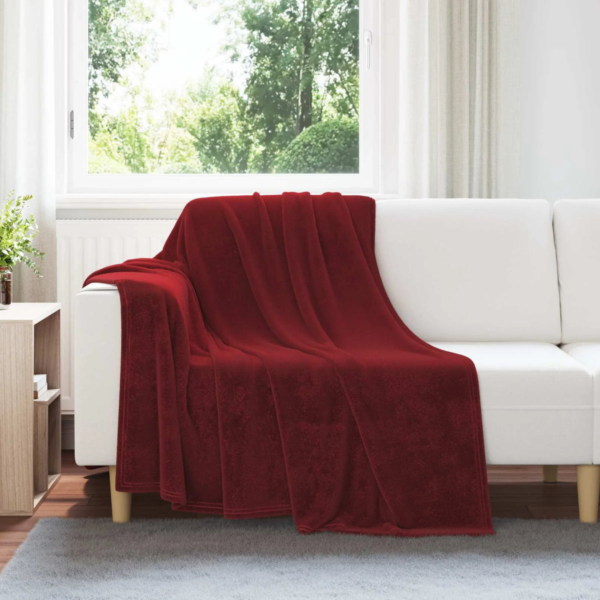 Couverture bordeaux drapée sur un canapé blanc