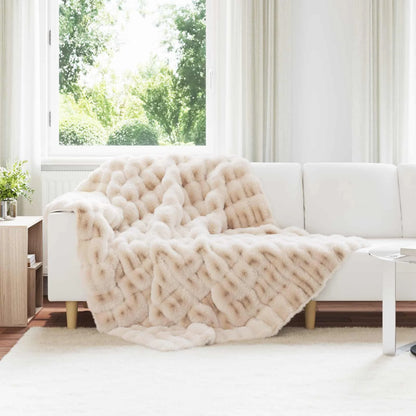 Couverture Fausse Fourrure, coloris beige, drapée sur un canapé blanc