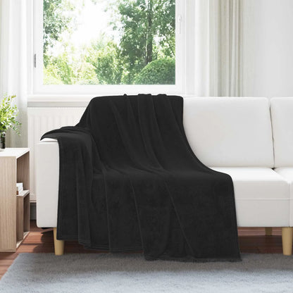 Couverture Noire, coloris noir, drapée sur un canapé blanc