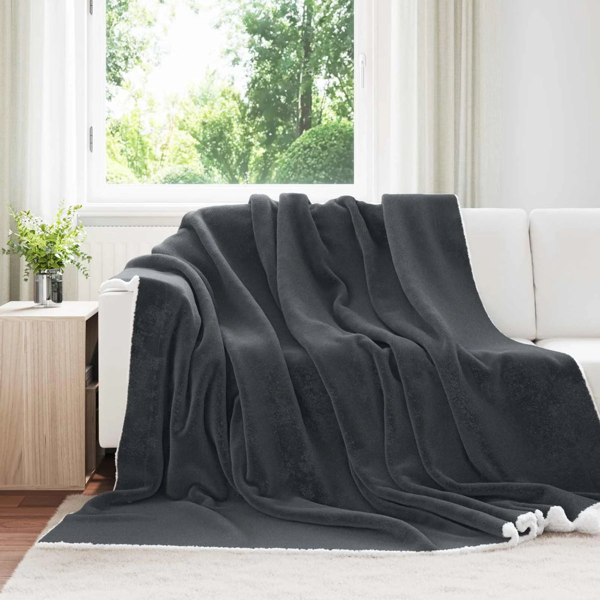 Couverture Polaire Épaisse, coloris gris foncé, drapée sur un canapé blanc