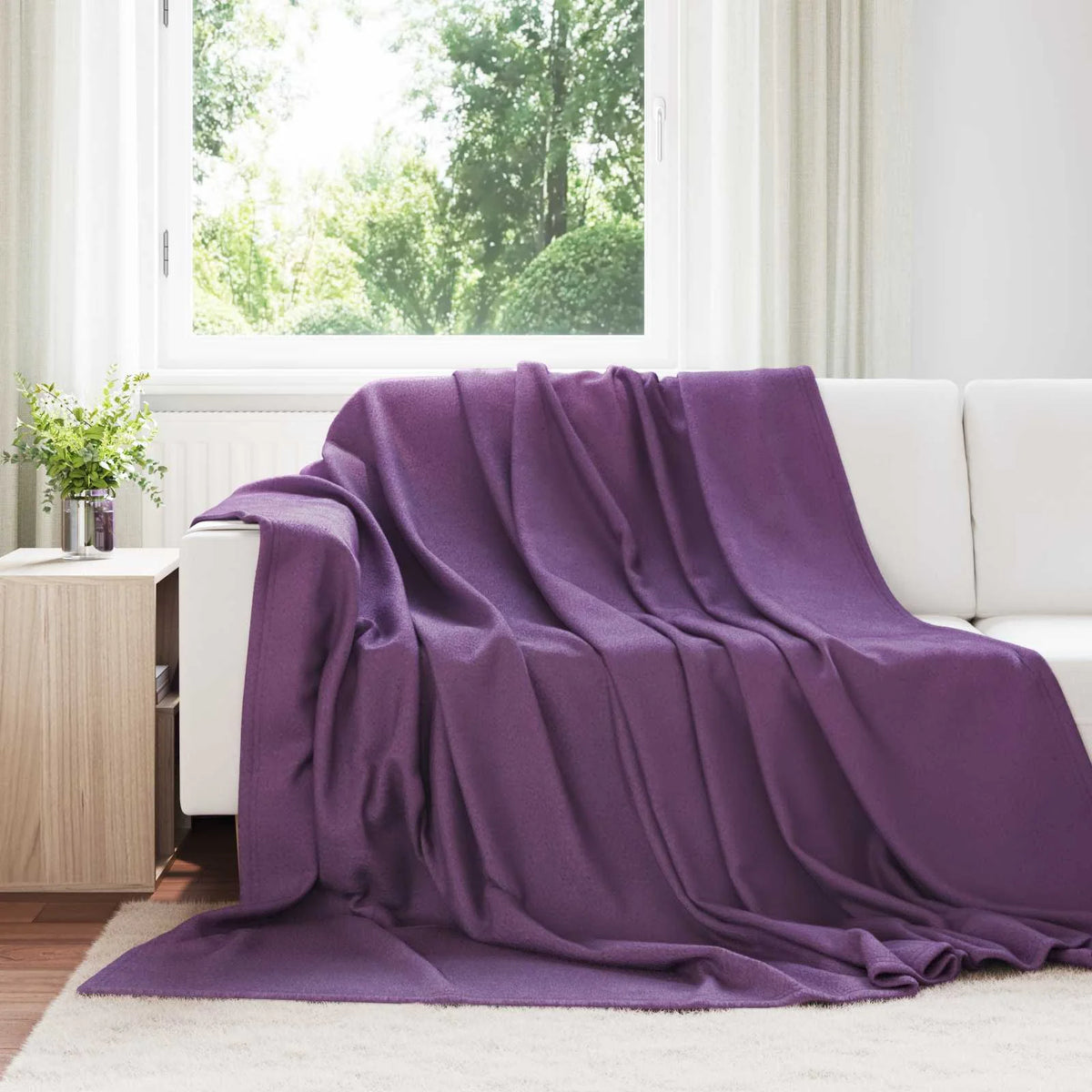Couverture Violette, coloris pourpre, drapée sur un canapé blanc