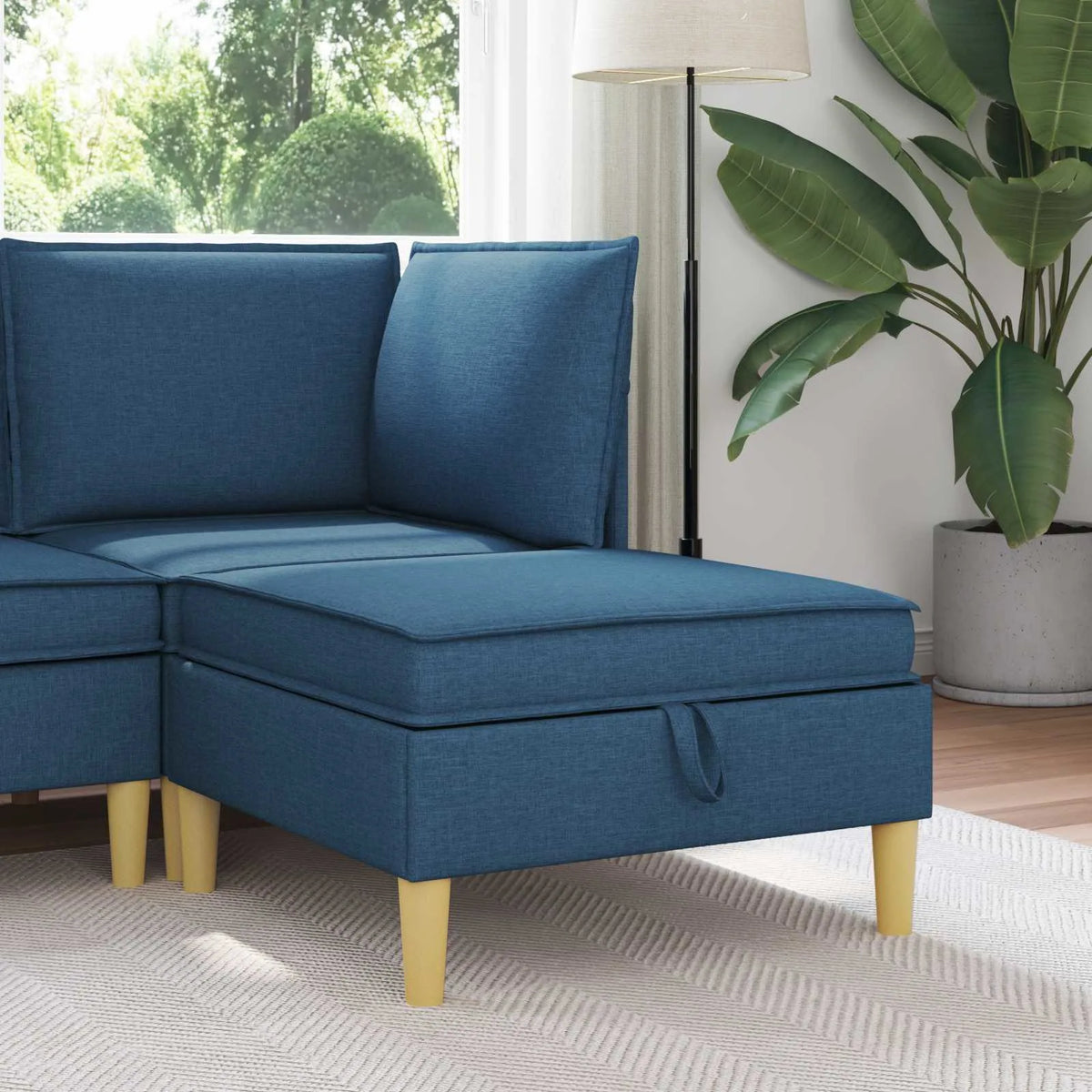Pouf de rangement bleu installé devant un canapé